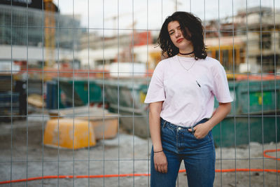 Portrait of woman standing against fence