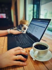 Midsection of woman holding coffee cup on table