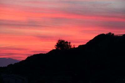 Scenic view of silhouette mountains against orange sky