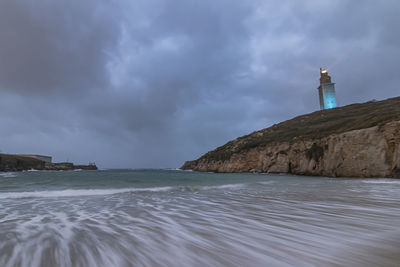 Lighthouse by sea against sky