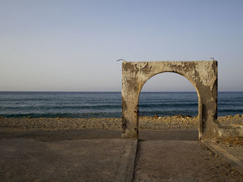 Arch at beach against clear sky