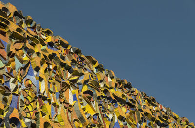 Low angle view of yellow wall against clear blue sky