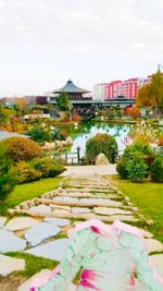 View of footpath by river and buildings against sky