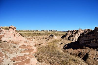 Rock formations on landscape against clear blue sky