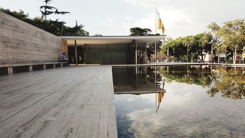 Reflection of building in swimming pool by lake against sky