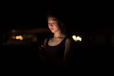 Young woman using mobile phone at nigh
