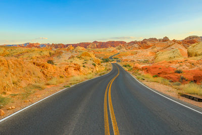 Road leading towards mountain against sky