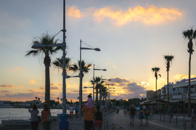 People at beach against sky during sunset