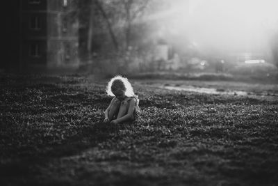 Side view of little girl sitting on field summer. black and white photography