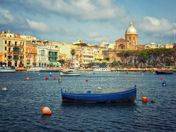 Boats in canal by buildings in city