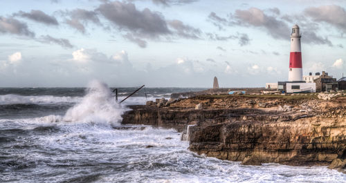 Lighthouse by sea against sky