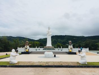 Statue in park against cloudy sky