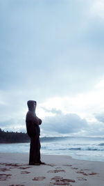 Statue on beach against sky