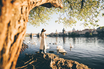 People standing on rock by lake against sky