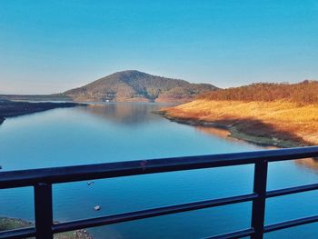 Scenic view of lake and mountains against clear blue sky