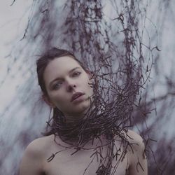 Portrait of young woman covered in twigs