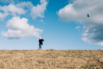 Rear view of man standing on field against sky