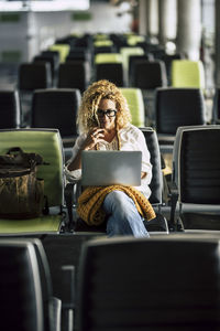 Woman using laptop while sitting at airport