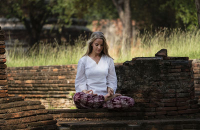 Woman sitting on stone wall