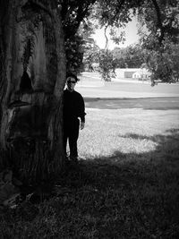 Rear view of man standing by tree trunk