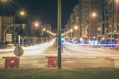 Light trails on road amidst buildings at night