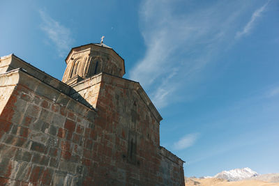 Gergeti trinity church of a mountain ridge and clouds, stepantsminda, kazbegi, georgia.