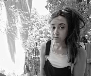 Portrait of young woman standing against plants