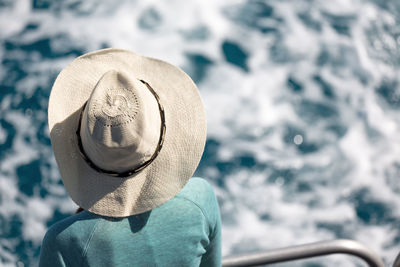 Rear view of woman wearing hat while standing by railing