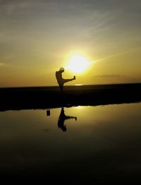 Silhouette person on lake against sky during sunset