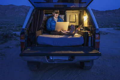 Hiker using laptop in car trunk during vacation