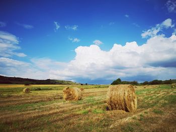 Hay bales on field against sky