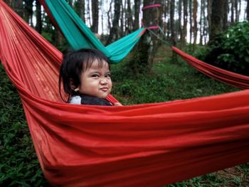 Portrait of happy boy sitting on hammock at playground