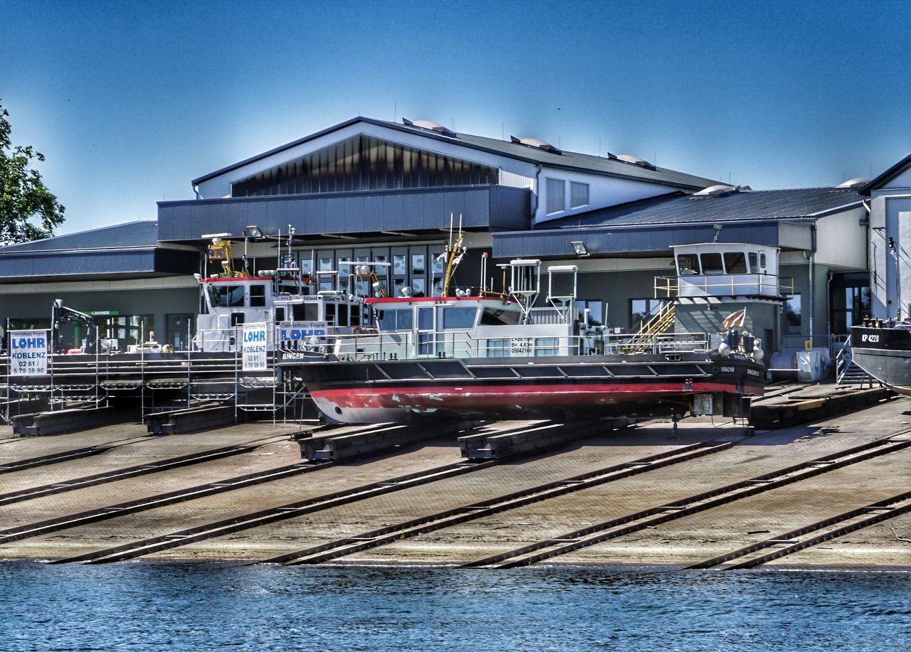 transportation, mode of transport, rail transportation, train - vehicle, built structure, day, outdoors, architecture, public transportation, railroad track, no people, nautical vessel, commercial dock, sky, building exterior, water