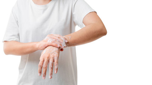 Midsection of woman holding hands against white background