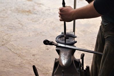 Midsection of blacksmith making horseshoe on anvil