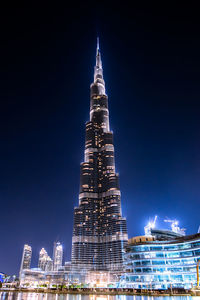 Low angle view of illuminated buildings against blue sky