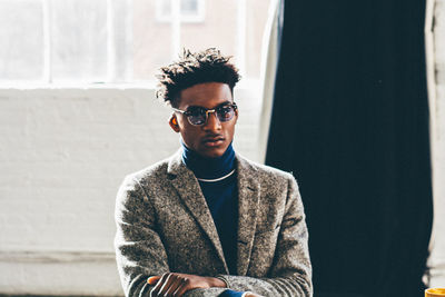 Portrait of young man standing against wall