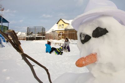 People on snow covered field with snowman