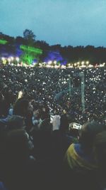 Crowd at music concert against sky at night