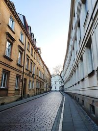 Empty road amidst buildings against sky