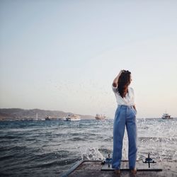 Rear view of man standing on beach against clear sky