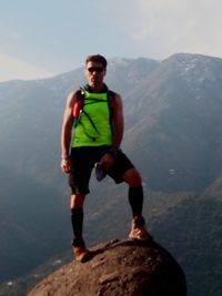 Young man standing on rock against mountains