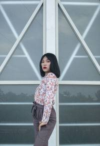 Portrait of woman standing against wall