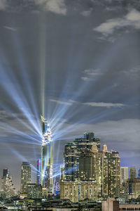 Illuminated city against cloudy sky