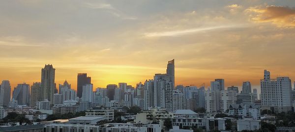 Modern buildings in city against sky during sunset