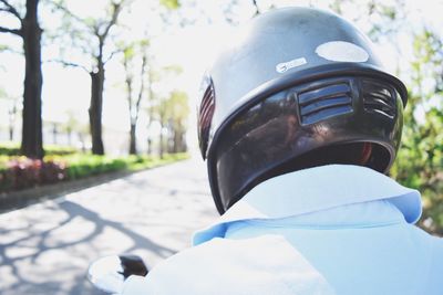 Rear view of man wearing helmet against trees