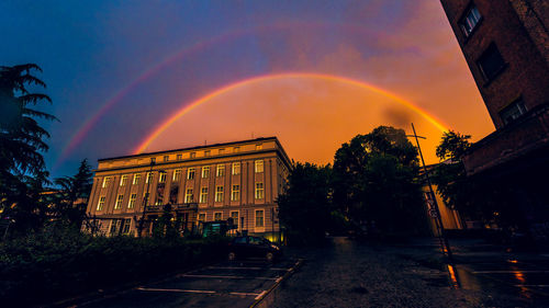 View of rainbow over buildings in city during sunset