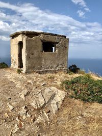 Old abandoned building by sea against sky