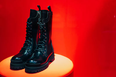 Black women's patent leather lace-up shoes on a boutique stand on a red background. copy space