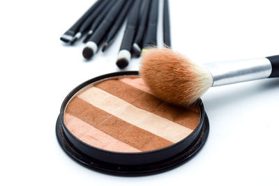 High angle view of make-up brushes with blush on white background